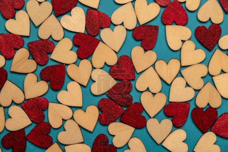 Foto de Top view of a composition of bright red and wood-colored hearts scattered on a blue surface - Imagen libre de derechos