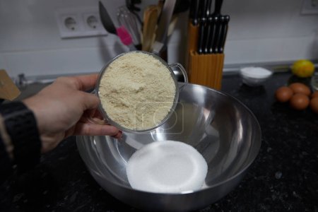 Foto de Anonymous person placing ground almonds on a bowl with sugar - Imagen libre de derechos