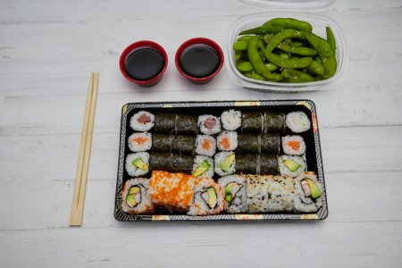 Foto de Top view of assorted sushi and rolls with soy sauce placed on wooden table - Imagen libre de derechos
