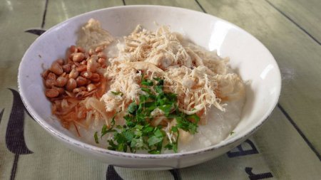 Foto de Bubur Ayam o gachas de pollo es un alimento tradicional indonesio de Bandung hecho de arroz blanco y servido con pollo rallado, cakwe, soja frita, galletas saladas, apio, cebolletas y huevo. - Imagen libre de derechos