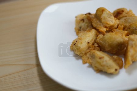 Nahaufnahme von Pisang Goreng Keju oder Gebratene Banane mit auf weißem Teller auf dem Holztisch.