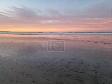 Téléchargez les photos : Découvrez la beauté à couper le souffle du coucher de soleil à Famara Beach, Lanzarote. Alors que le soleil descend sous l'horizon, le ciel se transforme en toile de teintes chaudes, projetant une lueur dorée sur les falaises escarpées et les eaux tranquilles de l'Atlantique. - en image libre de droit