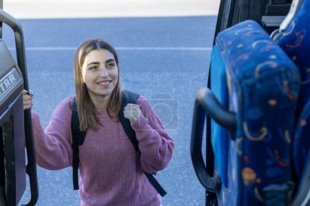 junges schönes Mädchen auf dem Hintergrund eines Busses mit einem Rucksack