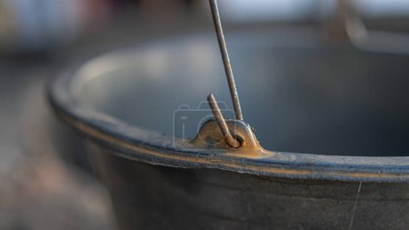 A rusty hook on the handle of a bucket