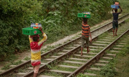 Téléchargez les photos : En septembre 01, 2018, des enfants du village de Sirajganj au Bangladesh vendaient de l'eau et des boissons gazeuses aux voyageurs des gares ferroviaires en transportant les marchandises dans leur tête. - en image libre de droit
