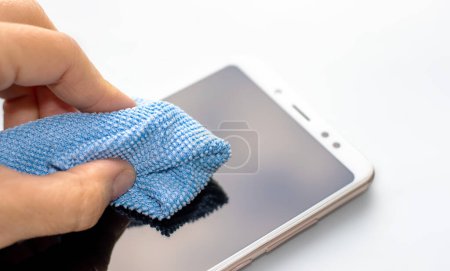 Photo for Maintenance and repairing smartphones. hand is cleaning phone screen with blue napkin. many tempered glass screen protector. mobile screen replacement protector. installation of protective cover film - Royalty Free Image