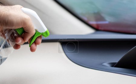 Téléchargez les photos : Car wash and interior chemical cleaning concept.hand use microfiber cloth and spray to clean lateral door from inside,retractable rear view mirror,steering wheel.modern hybrid vehicle clean inside - en image libre de droit