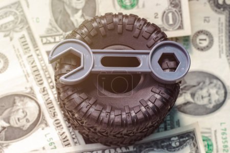 Foto de Tire replacement change concept.rubber black tires from toy car and plastic wrench key isolated.dollar bills toy car wheel.safety tyres change by yourself or in auto service.how to and mistakes - Imagen libre de derechos