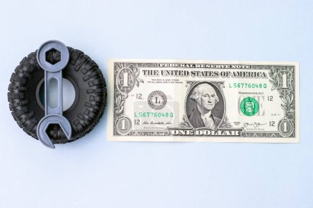Foto de Tire replacement change concept.rubber black tires from toy car and plastic wrench key isolated.dollar bills toy car wheel.safety tyres change by yourself or in auto service.how to and mistakes - Imagen libre de derechos