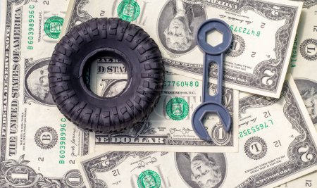 Photo for Tire replacement change concept.rubber black tires from toy car and plastic wrench key isolated.dollar bills toy car wheel.safety tyres change by yourself or in auto service.how to and mistakes - Royalty Free Image