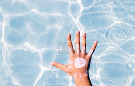Photo for Sun shape drawn from body spf uv protection cream lotion on teeneager girl or boy kid child hand shoulder against pool water.summer vacation red skin tan sun block cream - Royalty Free Image