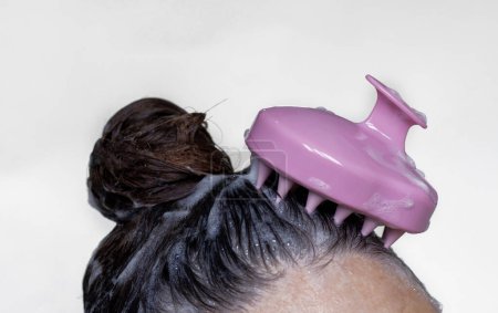 Téléchargez les photos : Hair growth stimulating, scalp massage.woman using pink scalp massager shampoo brush with silicone,flexible bristels.hair care,head relaxation.shampoo foam on hair,hand,isolated - en image libre de droit