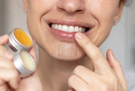 woman applying on lips balm or scrub from natural ingredients half bottom face kissing gesture smiling female.scrub and lip balm from small jars girl taking with finger rotation moves coconut oil