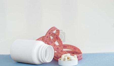 Foto de Frasco de pastillas blancas con cápsulas de vitamina c con estetoscopio y medir el peso tape.loss concepto de ajuste delgado nutrición saludable complementos alimenticios - Imagen libre de derechos