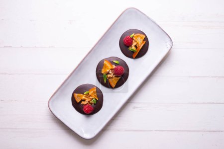 Téléchargez les photos : Chocolate dessert with candied orange, raspberry and nuts. - en image libre de droit