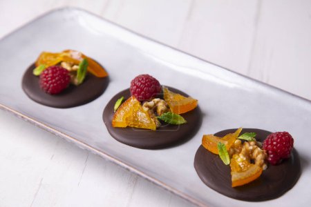 Téléchargez les photos : Chocolate dessert with candied orange, raspberry and nuts. - en image libre de droit