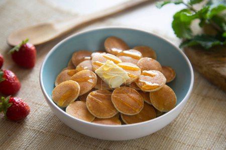 Téléchargez les photos : Mini crêpes au beurre et fruits rouges dans un bol. - en image libre de droit