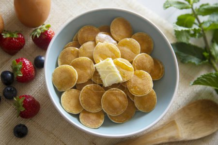 Téléchargez les photos : Mini crêpes au beurre et fruits rouges dans un bol. - en image libre de droit