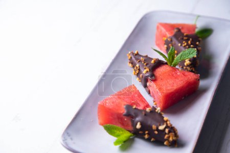 Photo for Chunks of fresh watermelon dipped in chocolate and covered with caramelized almonds. - Royalty Free Image