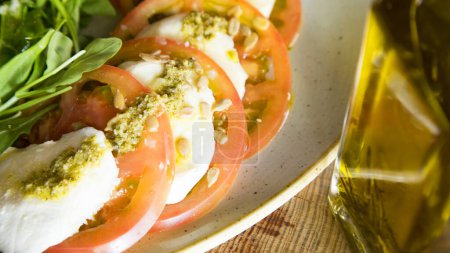 Foto de Ensalada Caprese es una ensalada italiana hecha de tomates en rodajas y mozzarella fresca, y hojas de albahaca fresca. - Imagen libre de derechos