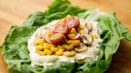 Téléchargez les photos : Hummus sur une feuille de salade avec maïs et radis. - en image libre de droit