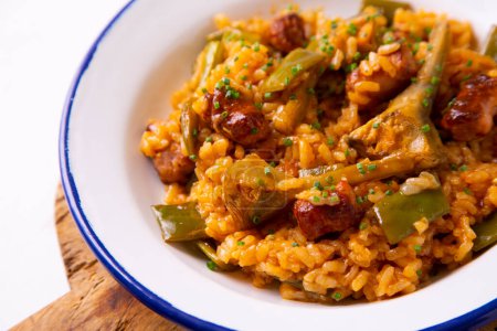 Téléchargez les photos : Paella traditionnelle espagnole aux saucisses, haricots verts et artichauts. - en image libre de droit