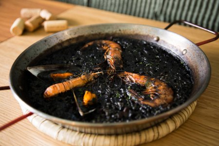 Foto de Paella negra tradicional española con mariscos hechos con tinta de calamar. - Imagen libre de derechos