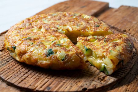 Photo for Spanish omelette with zucchini is an omelette to which chopped potatoes are added. It is one of the best-known and most emblematic dishes of Spanish cuisine - Royalty Free Image