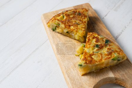 Photo for Spanish omelette with zucchini and ham is an omelette to which chopped potatoes are added. It is one of the best-known and most emblematic dishes of Spanish cuisine - Royalty Free Image