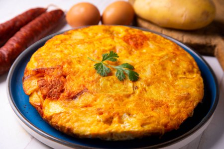 Photo for Spanish omelette with chorizo is an omelette to which chopped potatoes are added. It is one of the best-known and most emblematic dishes of Spanish cuisine - Royalty Free Image