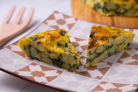 Photo for Spanish omelette with green spinach is an omelette to which chopped potatoes are added. It is one of the best-known and most emblematic dishes of Spanish cuisine - Royalty Free Image