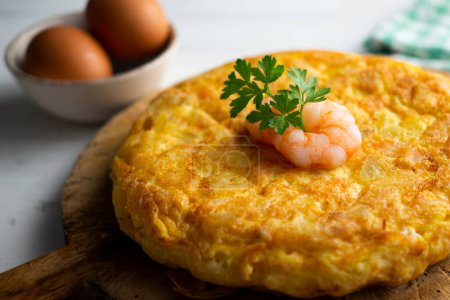 Photo for Spanish omelette with  prawns is an omelette to which chopped potatoes are added. It is one of the best-known and most emblematic dishes of Spanish cuisine - Royalty Free Image