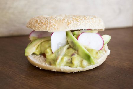Photo for Delicious avocado sandwich on bagel bread. A bagel is a bread traditionally made from wheat flour and usually has a hole in the center. - Royalty Free Image