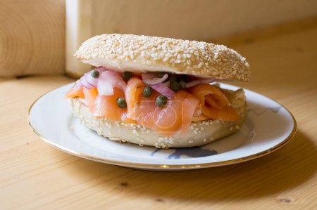 Téléchargez les photos : Délicieux sandwich au saumon sur pain bagel. Un bagel est un pain traditionnellement fabriqué à partir de farine de blé et a généralement un trou au centre. - en image libre de droit
