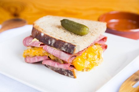 Photo for Delicious american pastrami and cheese sandwich decorated with a pickle. - Royalty Free Image