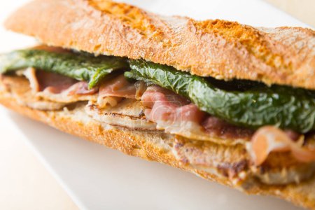 Photo for Serranito Sandwich. Typical Spanish sandwich with pork loin, bacon and fried green pepper. - Royalty Free Image