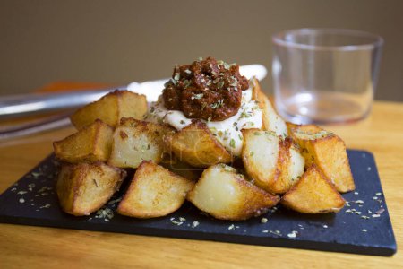 Photo for Papas bravas, are a typical preparation of bars in Spain consisting of potatoes cut into large cubes, fried in olive oil and seasoned with salsa brava, which is a spicy sauce. - Royalty Free Image