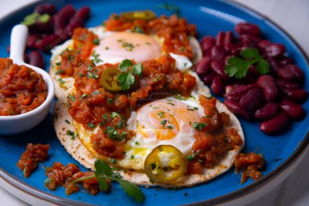Téléchargez les photos : Huevos rancheros sont un petit déjeuner mexicain traditionnel, qui se compose essentiellement de : œufs frits sur des tortillas de maïs avec une sauce à base de tomates, - en image libre de droit