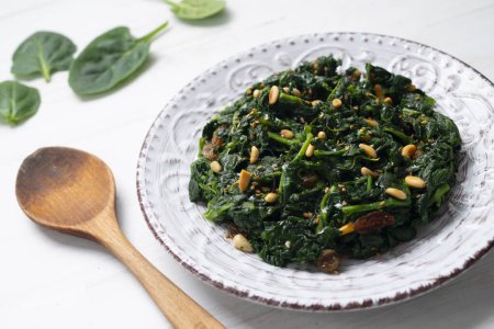 Photo for Spinach cooked in a pan with raisins, pine nuts and garlic. - Royalty Free Image