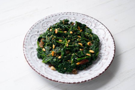 Photo for Spinach cooked in a pan with raisins, pine nuts and garlic. - Royalty Free Image