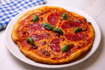 Téléchargez les photos : Pizza au salami. Pizza napolitaine à base de salami, fromage et légumes cuits au four. Recette végétarienne italienne. - en image libre de droit
