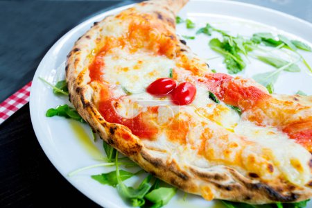 Foto de Calzone Pizza. Pizza napolitana rellena con queso, tomate y otros ingredientes como carne o verduras. Auténtica receta italiana. - Imagen libre de derechos