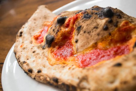 Foto de Calzone Pizza. Pizza napolitana rellena con queso, tomate y otros ingredientes como carne o verduras. Auténtica receta italiana. - Imagen libre de derechos