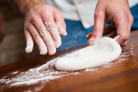 Photo for Preparing a pizza by kneading the dough and cooking with Italian homemade tomato sauce. - Royalty Free Image