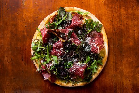 Photo for Pizza beef carpaccio. Neapolitan pizza made with tomato sauce, cheese and beef. Italian recipe. - Royalty Free Image