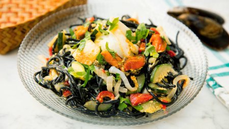 Téléchargez les photos : Recette de pâtes Nero di settlefish frutti di mare. Pâtes combinées avec moules, palourdes et crevettes, tomates frites et ail - en image libre de droit