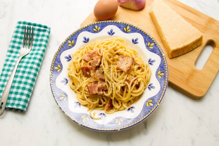 Photo for Carbonara or Carbonata is an Italian pasta dish originating from Lazio, and more specifically from Rome. The original recipe is based on eggs, cheese, extra virgin olive oil, pancetta or guanciale and black pepper. - Royalty Free Image