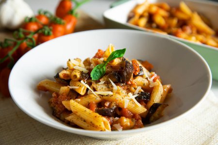 Photo for Pasta alla Norma is a traditional pasta dish of Sicilian cuisine, widely celebrated in the Italian city of Catania. It is a pasta dish made, in most cases, with maccheroni, aubergines, tomatoes, fresh basil and ricotta grated salata. - Royalty Free Image