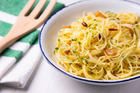 Photo for Spaghetti aglio e olio is a traditional Italian pasta dish from Naples. The dish is prepared by lightly sauting minced or pressed garlic in olive oil, sometimes with the addition of dried cayenne, and tossing the spaghetti. - Royalty Free Image