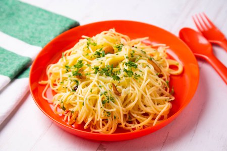 Téléchargez les photos : Spaghetti aglio e olio est un plat traditionnel italien de pâtes de Naples. Le plat est préparé en sautillant légèrement l'ail haché ou pressé dans l'huile d'olive, parfois avec l'ajout de Cayenne séchée, et en jetant les spaghettis. - en image libre de droit